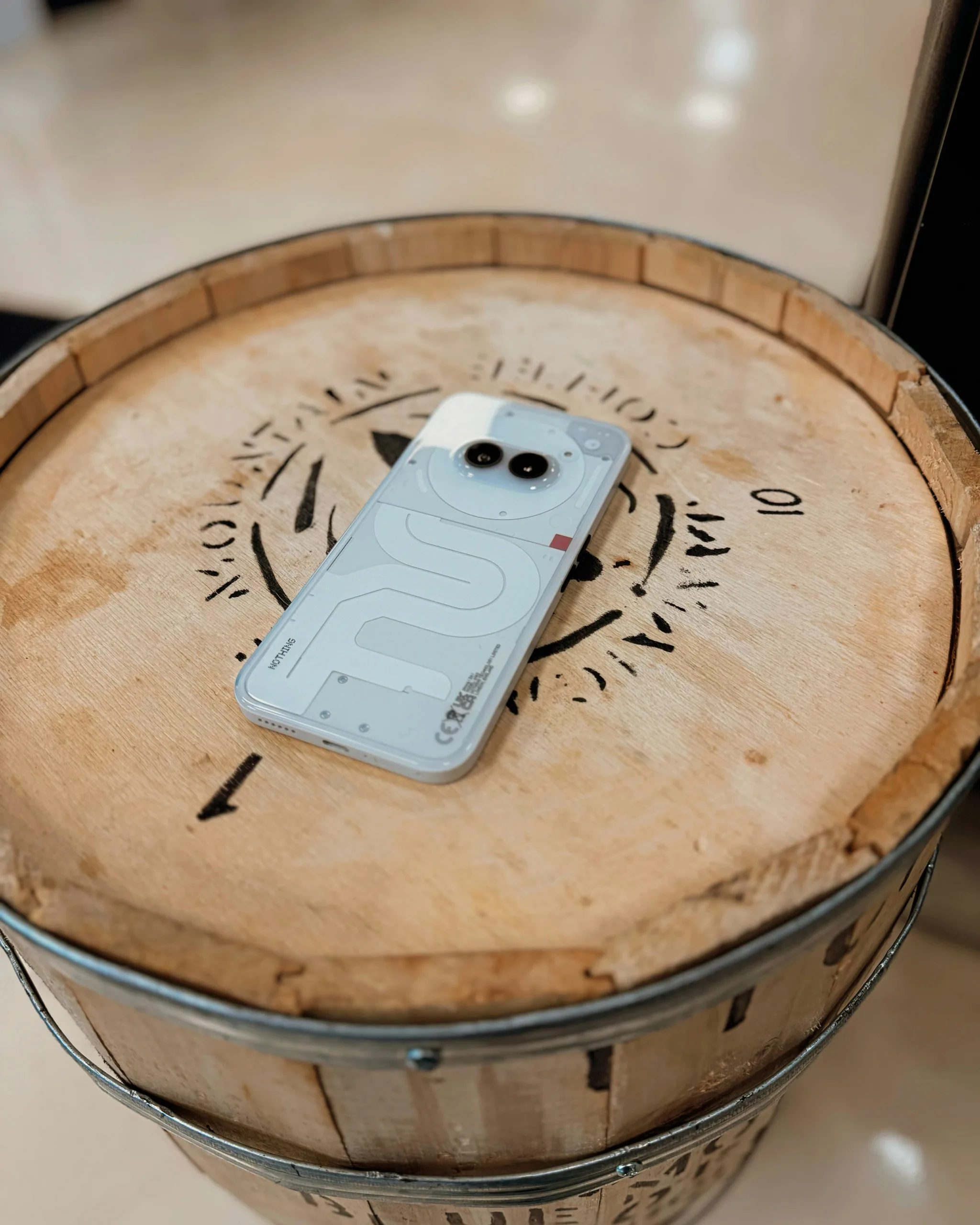 a cell phone Nothing Phone 2A sitting on top of a wooden barrel